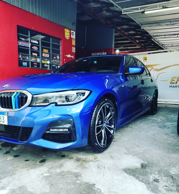 BMW azul dentro da oficina, com o letreiro da Express Martelinho de Ouro ao fundo